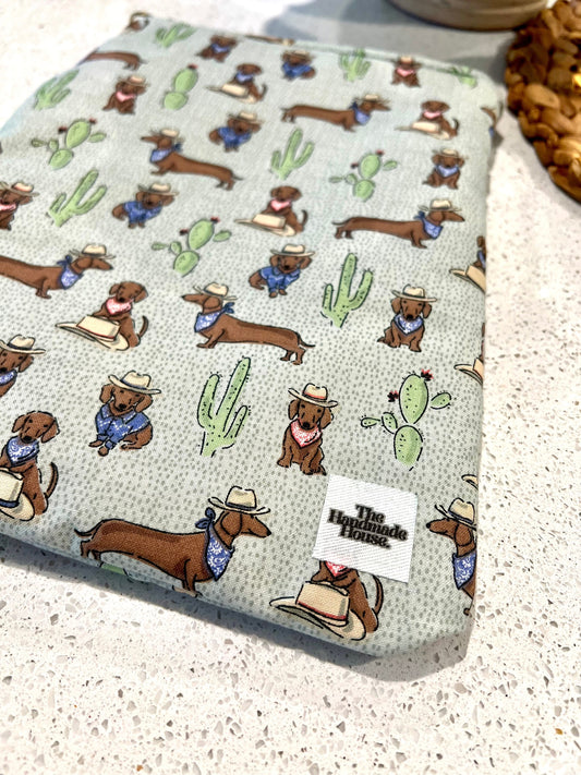 Dachshund-themed small quilted book sleeve with zipper closure.