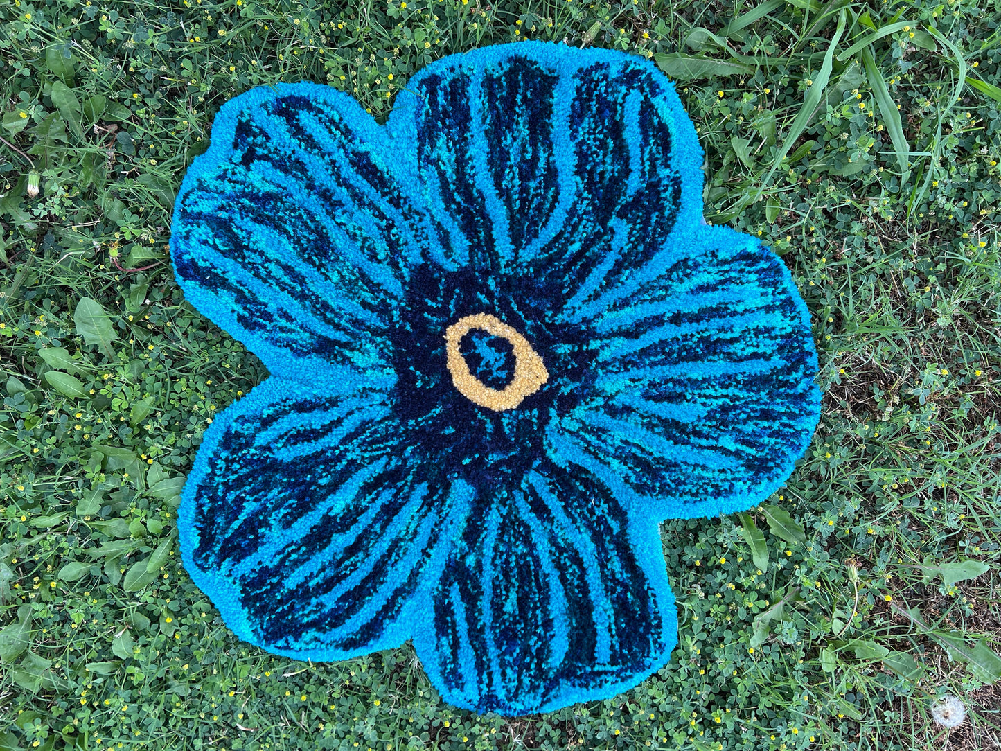 Blue Flower rug on green grass.