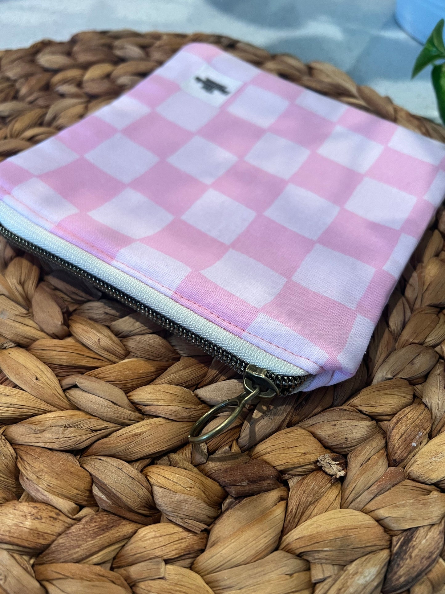 Pink checkered mini pouch on woven surface.