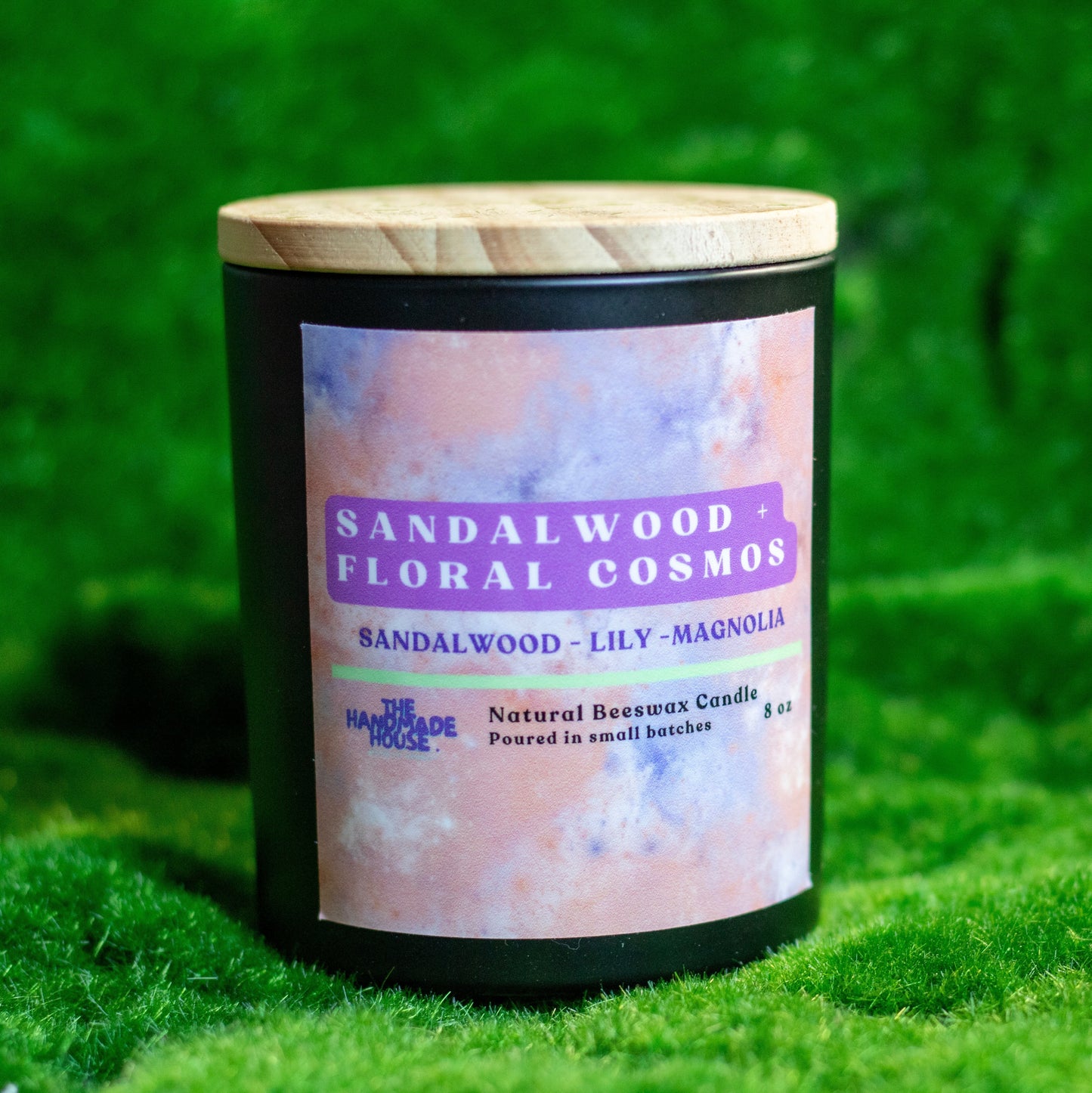 Sandalwood and Floral Cosmos natural beeswax candle with wooden lid on grass background.