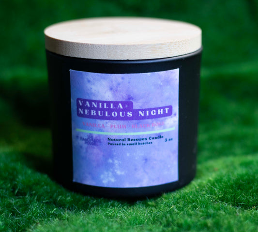 Vanilla + Nebulous Night Beeswax Candle with wooden lid on green background.