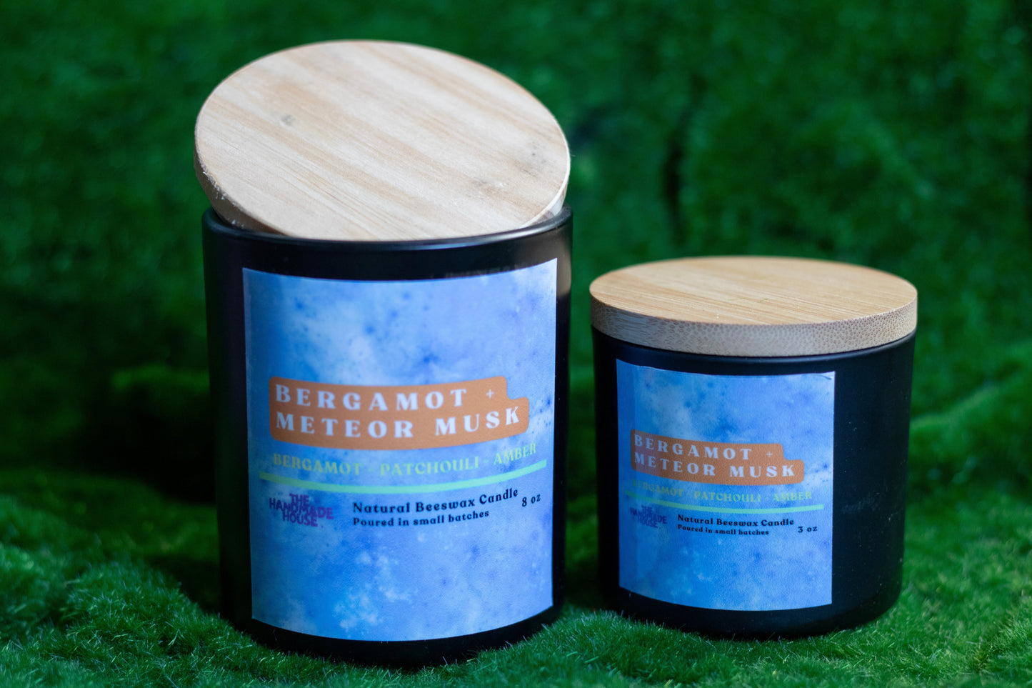 Bergamot + Meteor Musk Beeswax Candle in 8oz and 3oz sizes with wooden lids on green background.
