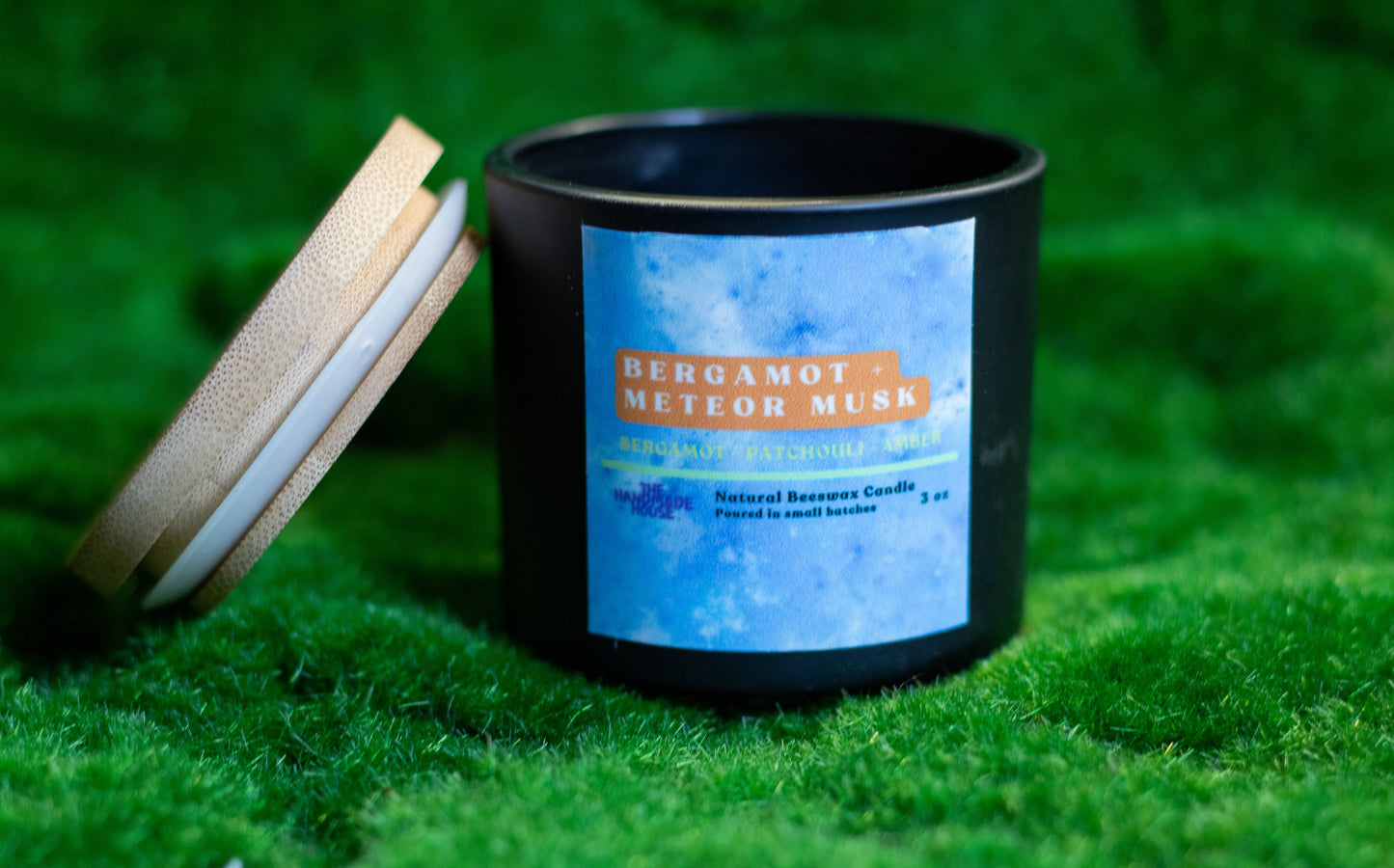 Bergamot + Meteor Musk Beeswax Candle with reusable minimalist vessel and wooden lid on grass.