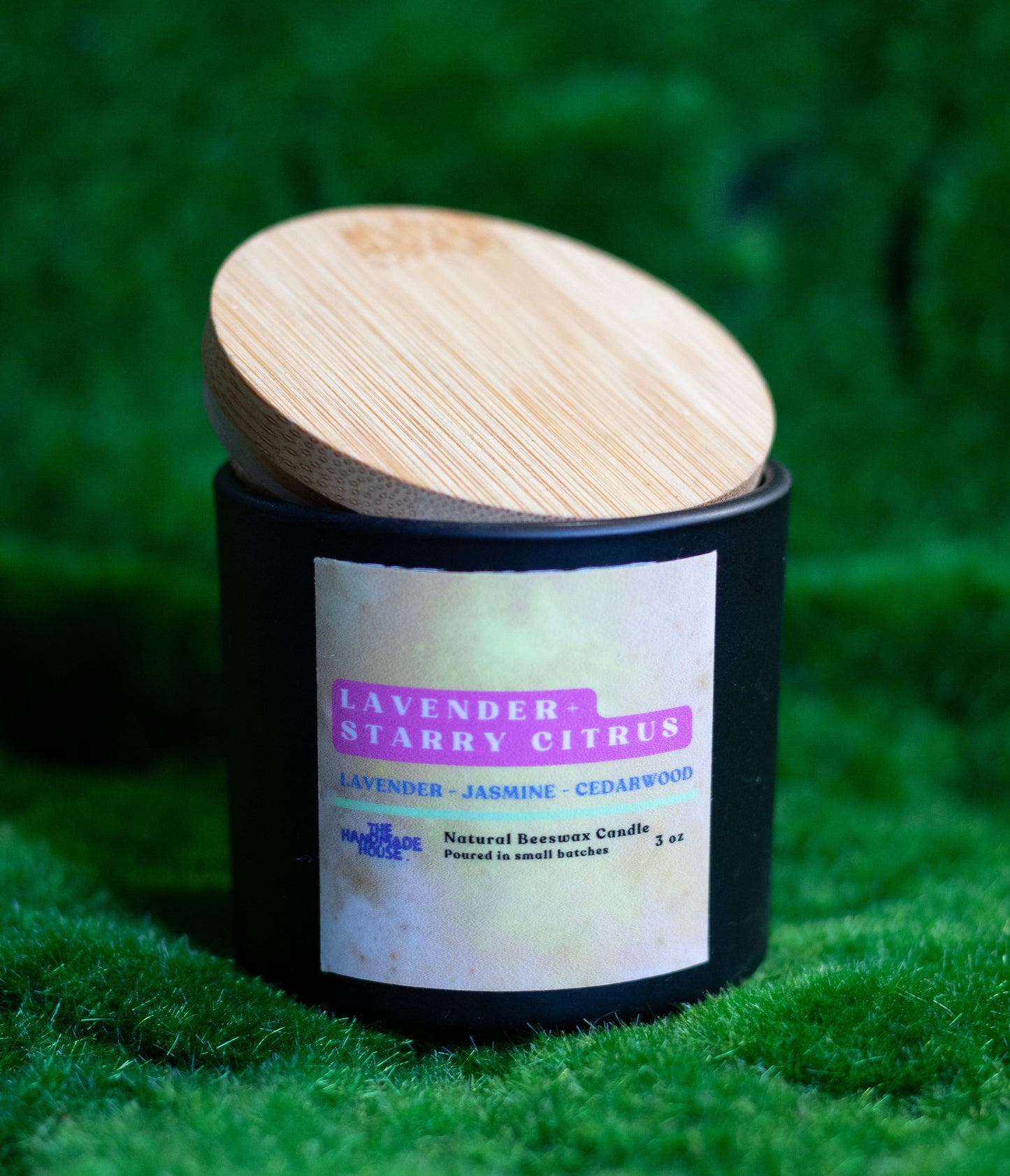 Lavender + Starry Citrus Beeswax Candle with wooden lid on grass background.