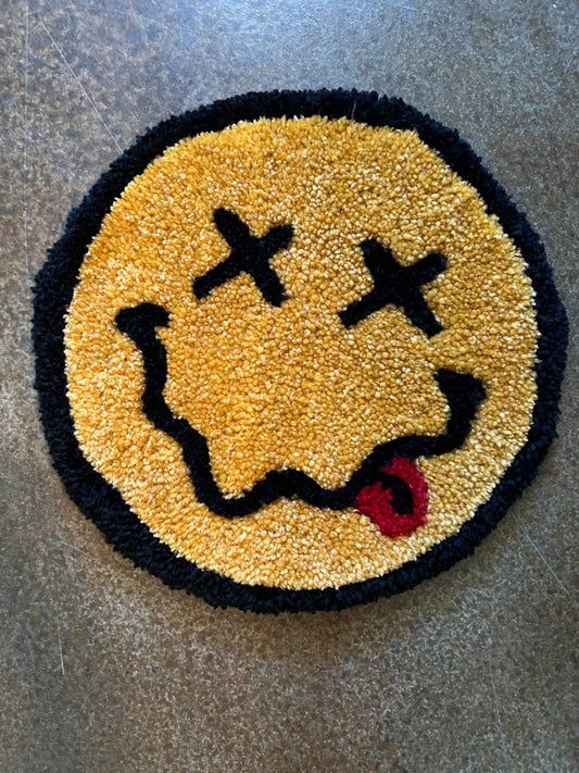 Classic Smiley Face rug with crossed eyes and red tongue, 12x12 inches.