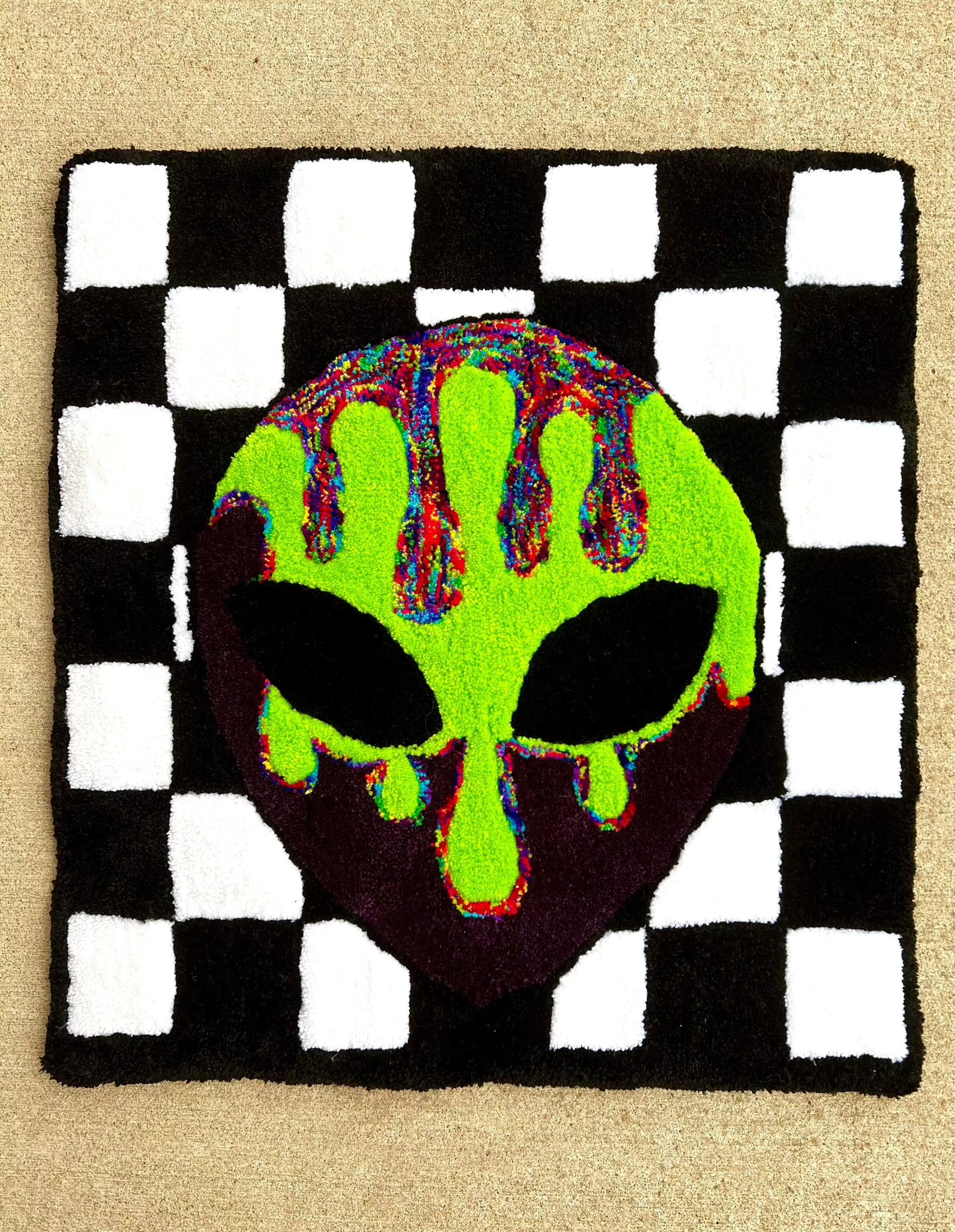Checkered alien head rug with neon green, black, and multicolored pattern, size 28x26 inches.
