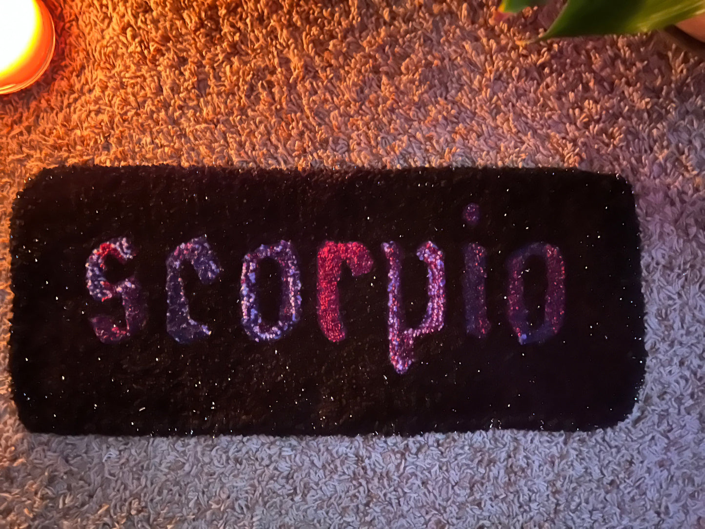 Custom Scorpio zodiac sign rug, 21x9 inches, displayed on carpet with candlelight effect.