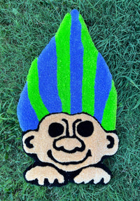 Neon Troll rug with vibrant green and blue hair on grass.