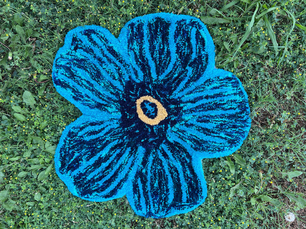 Blue Flower rug on green grass.