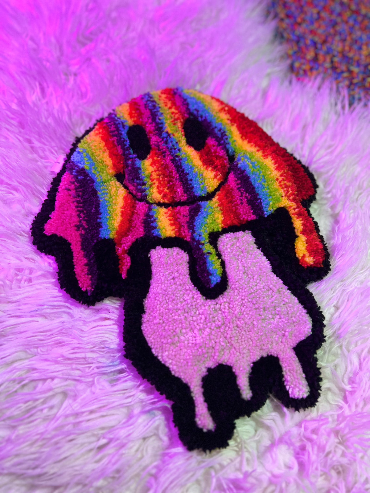 Colorful rainbow mushroom rug with a smiley face on a furry background.