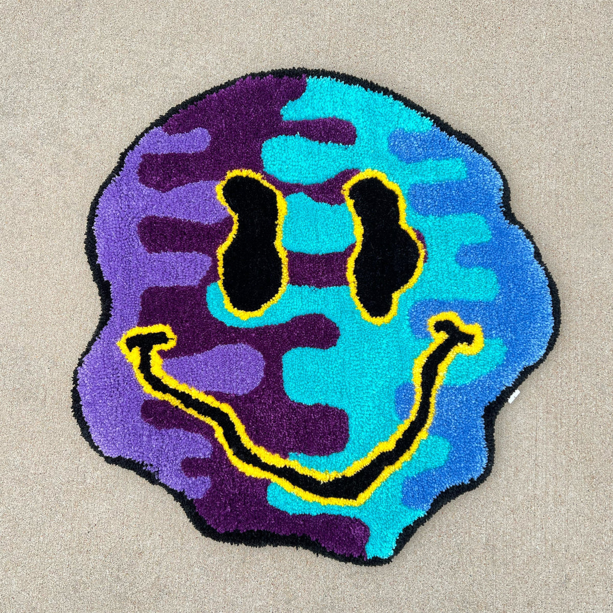 Colorful smiley face rug, 25x25 inches, in black, yellow, light blue, dark blue, and purple hues.