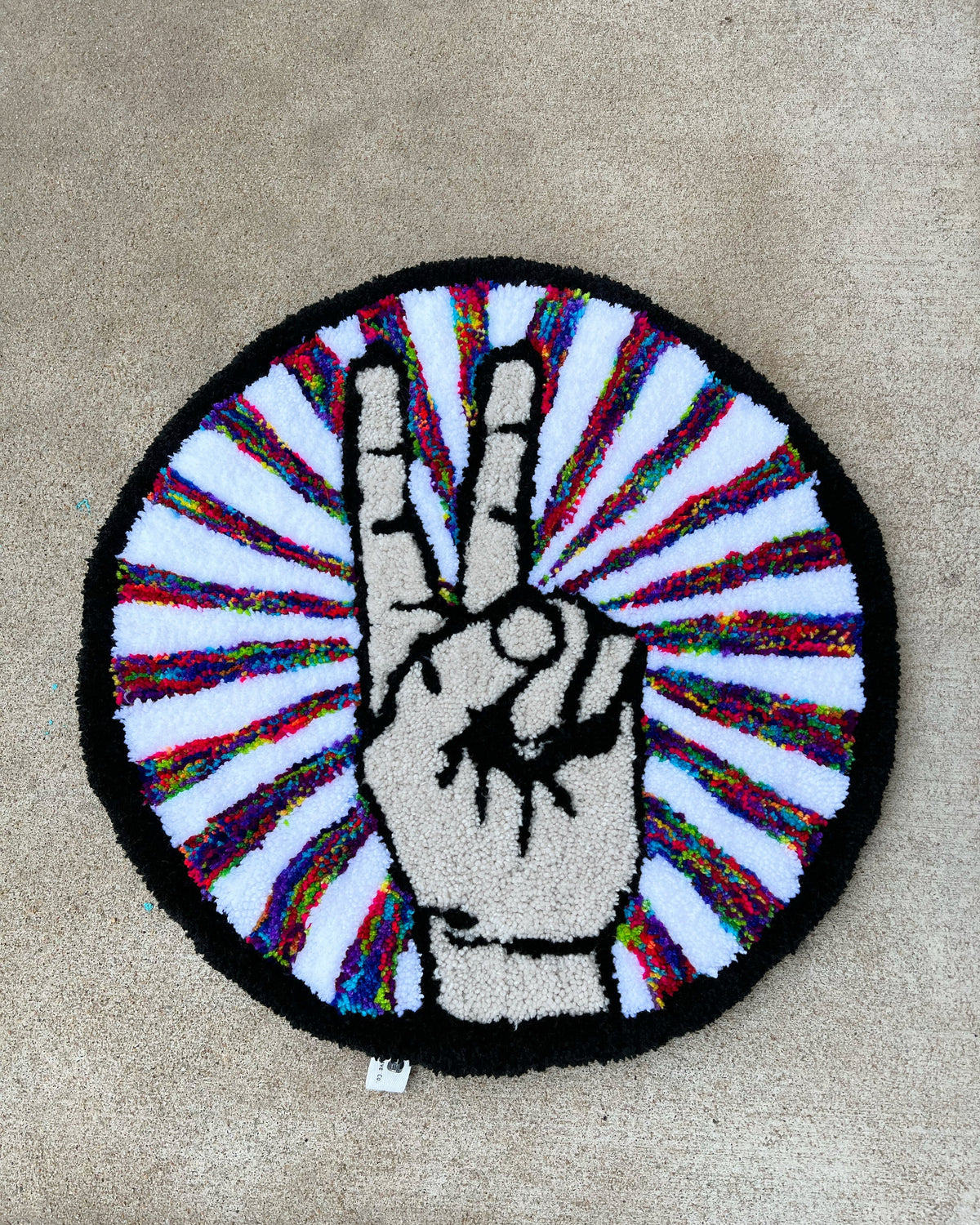 Peace Sign Rug in black, tan, and multicolor, 19x19 inches.