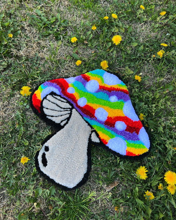 Rainbow-patterned mushroom rug with tan stem on grass, available in size 15x16 inches from Drop 2 collection.