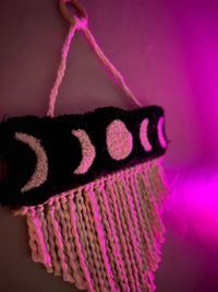 Moon phase wall hanging with fringes, size 21x13 inches, glowing under pink light.